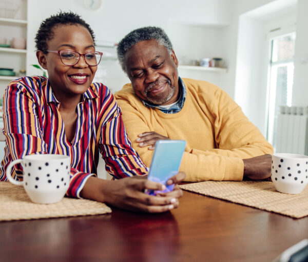 African American senior couple using a smartphone at home.